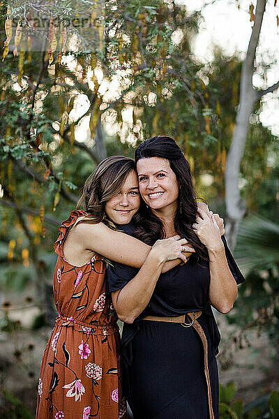 Teenager-Tochter umarmt Mutter im Garten in San Diego