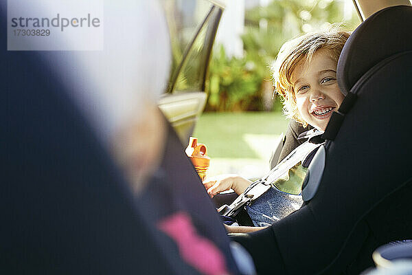 Niedlicher Junge lächelnd im Auto sitzend