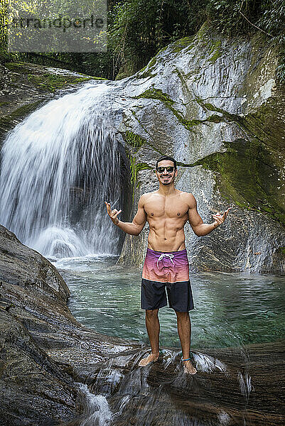 Mann genießt schönes kristallklares Wasser Regenwald Wasserfall