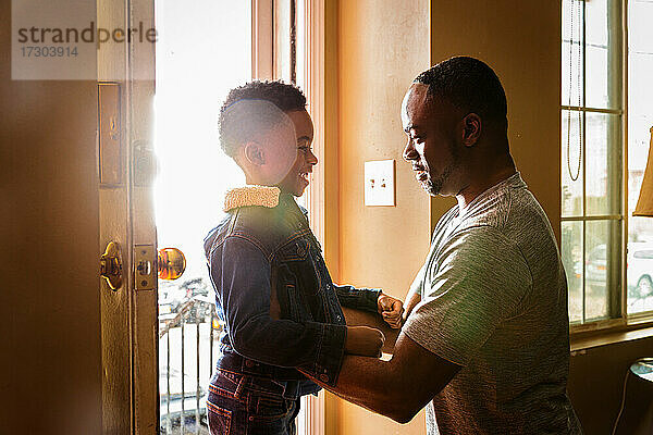 Seitenansicht eines lächelnden Sohnes mit seinem Vater am Eingang des Hauses