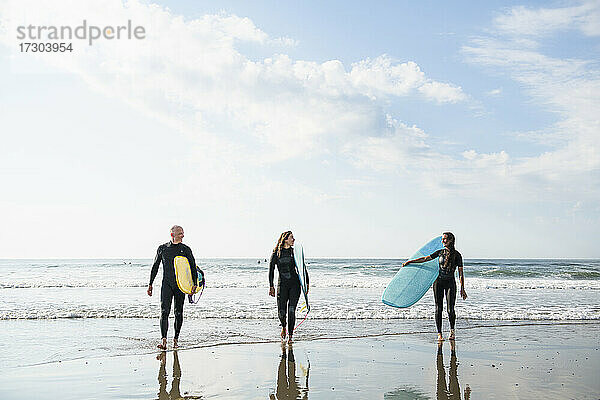 Gruppe von Surferfreunden beim Surfen im Sommer bei Sonnenaufgang