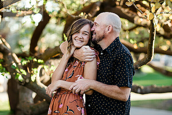 Vater umarmt Teenager-Tochter im Garten in San Diego