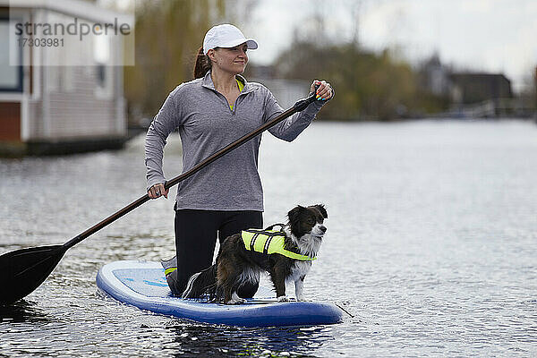 Eine Frau und ihr Hund paddeln auf einer Gracht in den Niederlanden