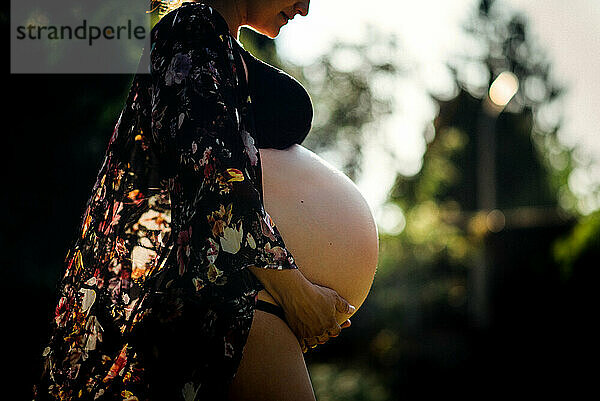 Seitenansicht der schwangeren Frau mit großem Bauch draußen in der Natur