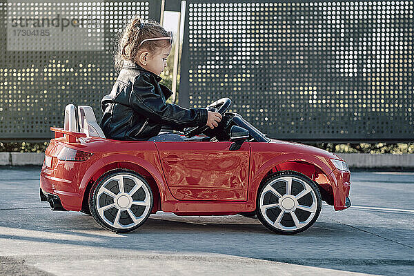 Ein Mädchen fährt ein Spielzeugauto