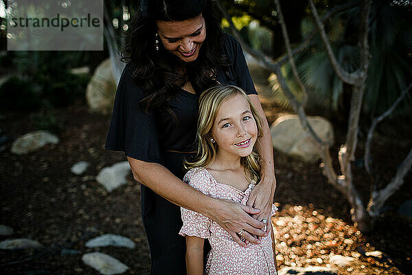 Mutter umarmt junge Tochter im Garten in San Diego