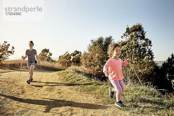 Fröhliches Mädchen wandert mit Mutter gegen den klaren Himmel an einem sonnigen Tag