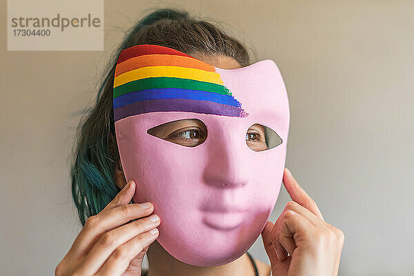 Frau bereitet sich mit handgefertigter Maske mit LGBTI-Flagge auf den Pride Day vor