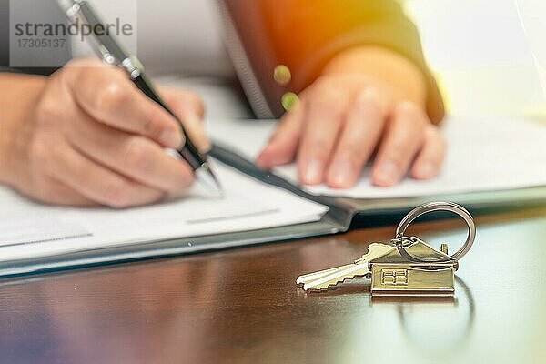 Frau Unterzeichnung Immobilien Vertrag Papiere mit Hausschlüssel und nach Hause Schlüsselbund in vor