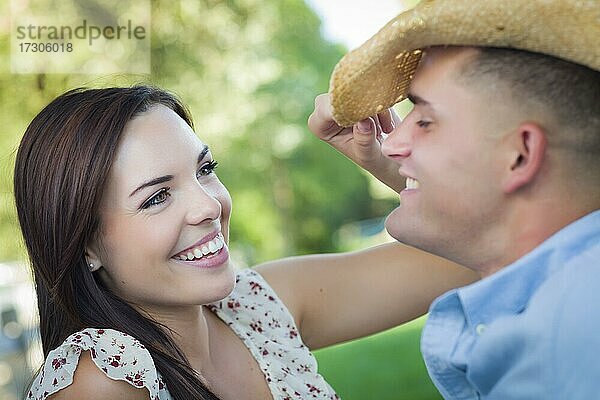 Glückliches gemischtrassiges romantisches Paar mit Cowboyhut flirtet im Park