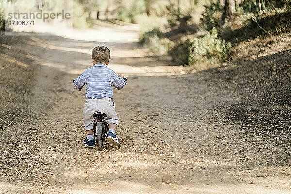 Zurück von niedlichen Kleinkind Fahrrad fahren auf Feldweg im Wald