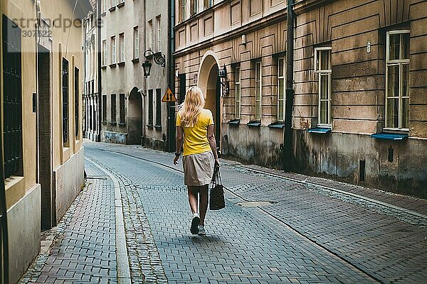 Frau in gelbem T-Shirt  geht zu Fuß durch die alten Straßen von Warschau  Polen  Europa