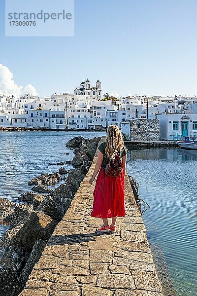Junge Frau mit rotem Kleid auf Hafenmauer  Hafenstadt Naoussa  Insel Paros  Kykladen  Griechenland  Europa
