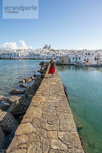 Junge Frau mit rotem Kleid auf Hafenmauer  Hafenstadt Naoussa  Insel Paros  Kykladen  Griechenland  Europa
