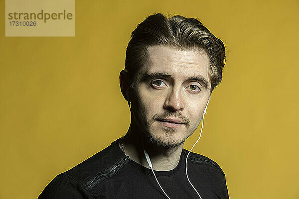 Porträt selbstbewusster junger Mann  der mit Kopfhörern Musik hört