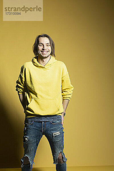 Porträt glücklicher junger Mann in Sweatshirt und zerrissenen Jeans