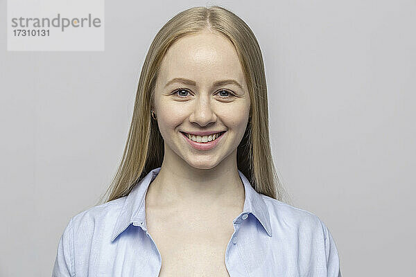 Studio Porträt zuversichtlich lächelnde junge Frau auf grauem Hintergrund