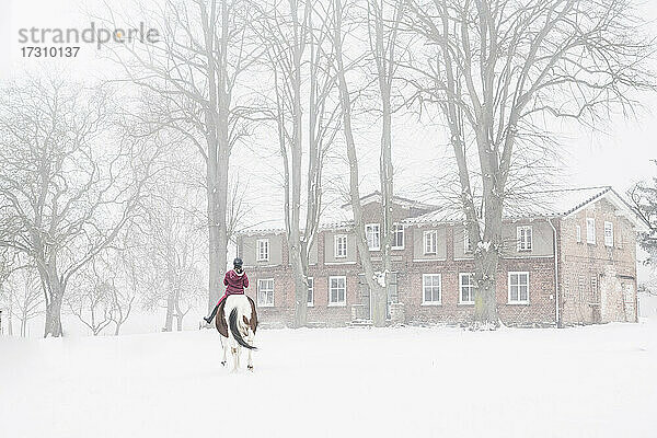 Mädchen reitet Pferd im Schnee draußen