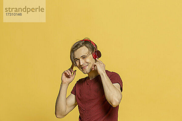 Porträt glücklicher junger Mann  der mit Kopfhörern Musik hört