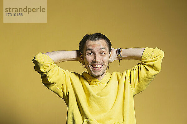 Porträt aufgeregt  glücklich junger Mann auf gelbem Hintergrund