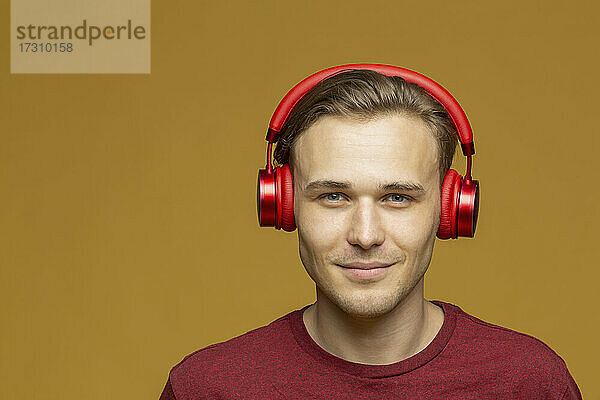 Studio Porträt selbstbewusst junger Mann hört Musik mit Kopfhörern