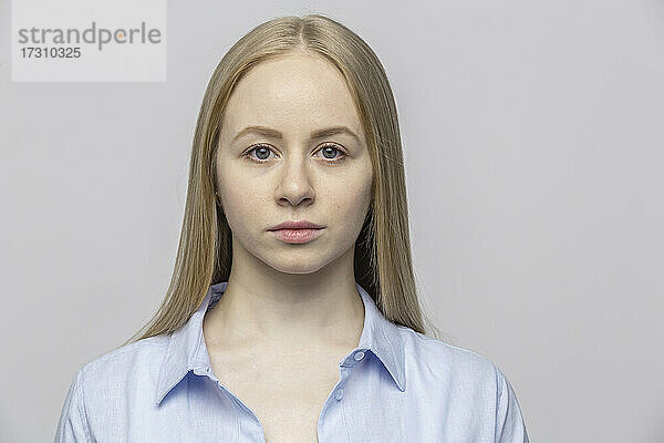 Porträt ernste junge Frau gegen grauen Hintergrund