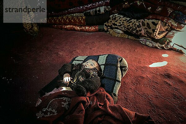 Kleinkind einer Nomadenfamilie liegt in einer Jurte auf dem Boden  dahinter Teppiche und Decken  Wakhan-Korridor  Badachschan  Afghanistan  Asien