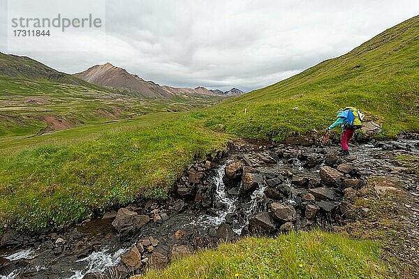 Mädchen überquert Bachlauf  Brúnavík  Víknaslódir  Island  Europa