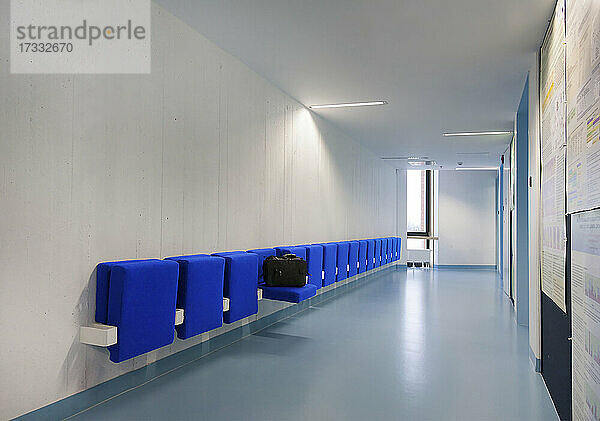 Langer Korridor in einer modernen Berufsschule mit blauen Sitzen.