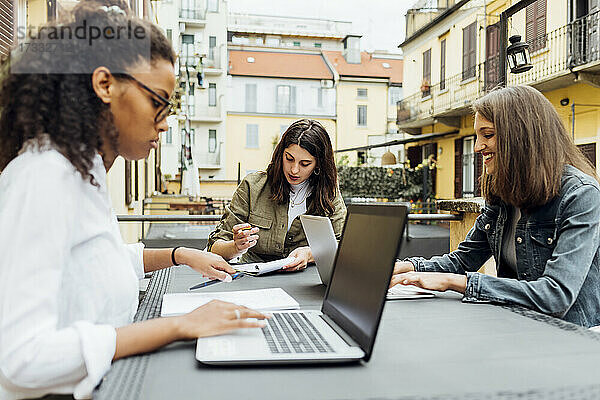 Geschäftsfrauen mit Laptop auf der Terrasse sitzend