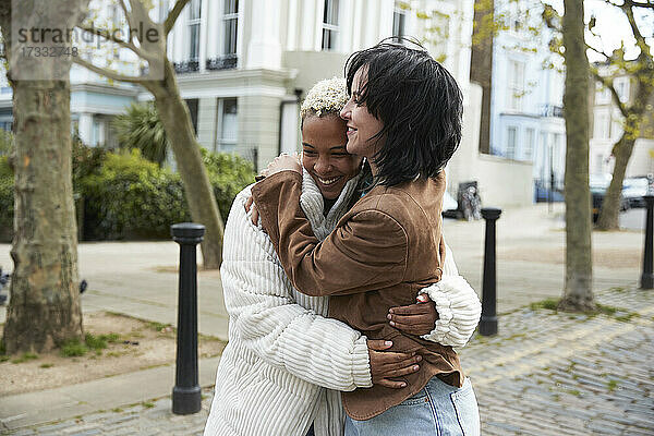 Glückliches lesbisches Paar  das sich umarmt und auf dem Fußweg steht