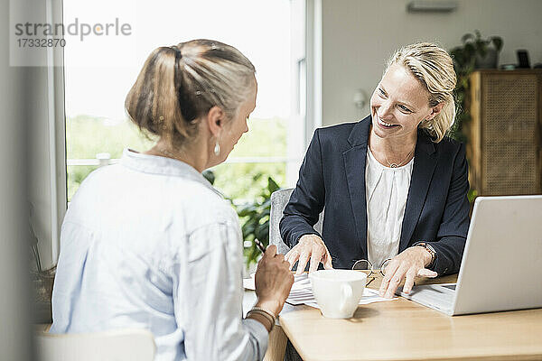 Geschäftsfrau erklärt Kunden  während sie im Büro sitzt