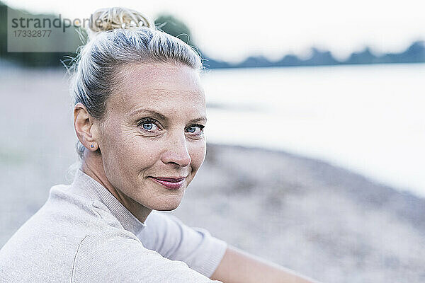 Lächelnde blonde Frau am Flussufer