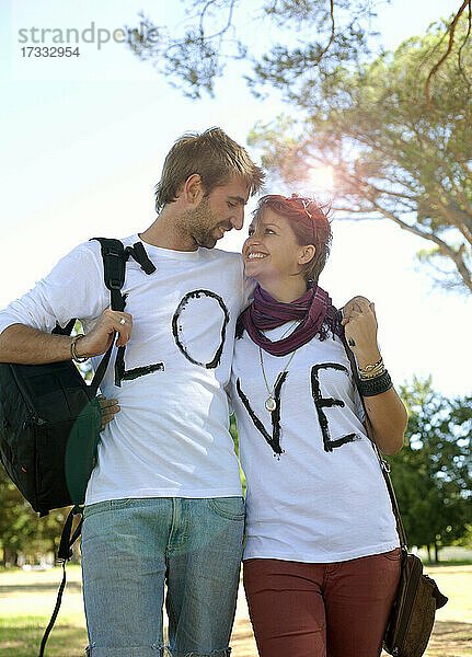 Verliebtes Paar in T-Shirts mit Liebestext  das sich in einem öffentlichen Park ansieht