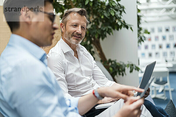 Männliches professionelles Team bei der Verwendung eines digitalen Tablets im Büro