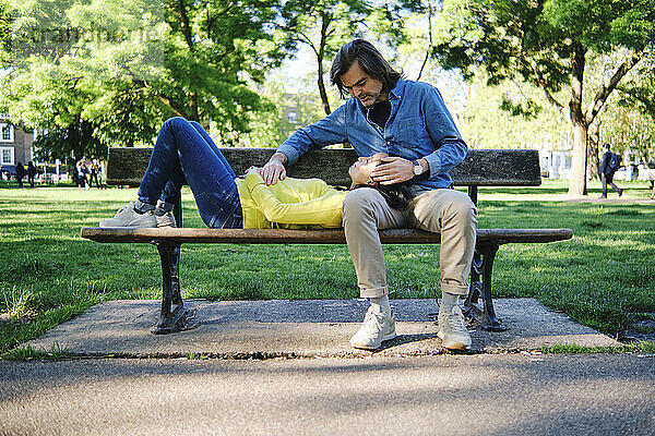 Mann streichelt auf dem Schoß liegende Frau in einem öffentlichen Park