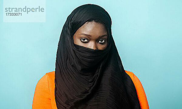 Junge Frau mit Hidschab vor blauem Hintergrund