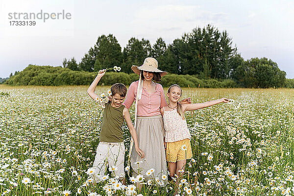 Mutter steht mit Kindern inmitten von Blumen auf einem Feld