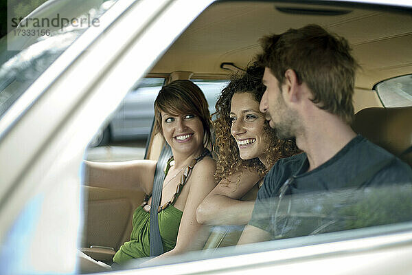 Lächelnde weibliche und männliche Freunde im Auto während einer Autoreise