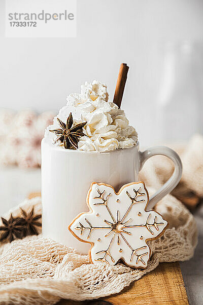 Weihnachtsplätzchen in Form einer Schneeflocke und eine Tasse mit heißem  schaumigem Chai