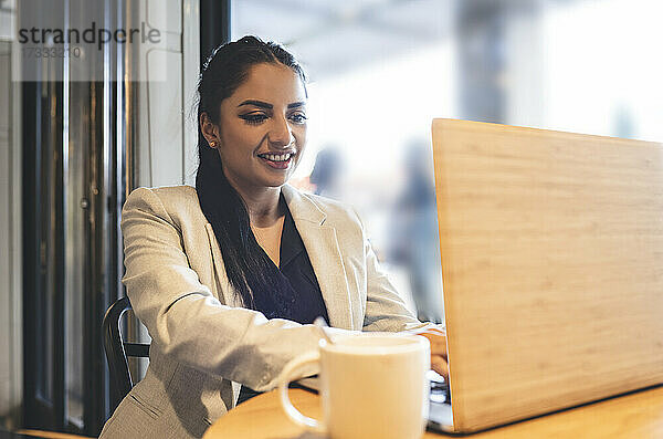 Berufstätige Frau benutzt Laptop bei der Arbeit in einem Cafe