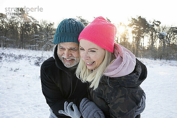 Lächelnder Mann umarmt Frau im Winter