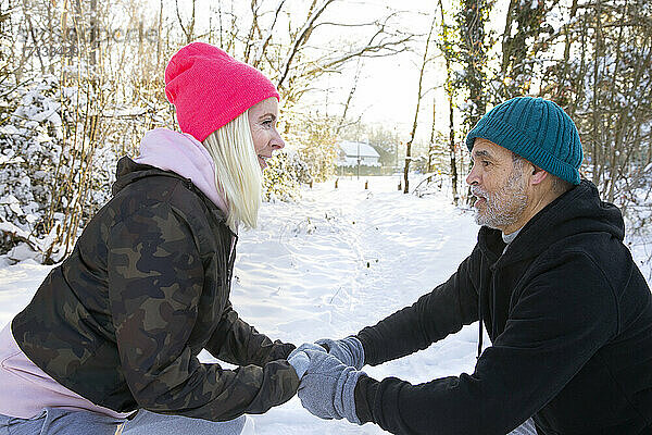 Paar hält sich an den Händen  während es gemeinsam im Schnee trainiert