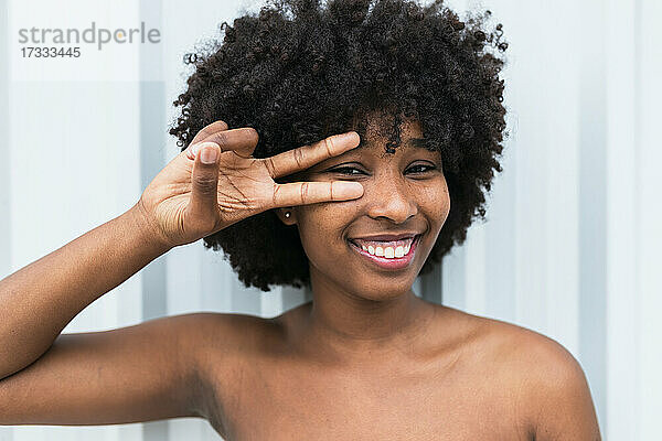 Lächelnde Afro-Frau  die vor einer Wand gestikuliert