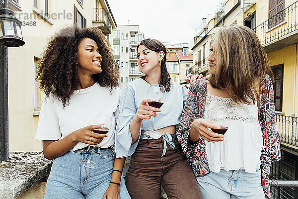 Freunde mit Weingläsern unterhalten sich auf der Terrasse miteinander