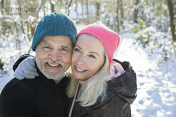 Älteres Paar mit Wange an Wange lächelnd im Wald