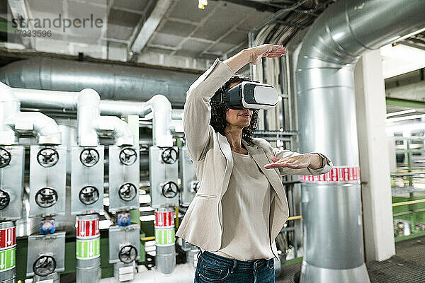 Weiblicher Experte gestikuliert bei der Verwendung eines Virtual-Reality-Headsets in der Industrie
