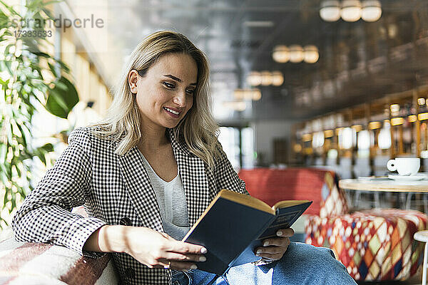 Lächelnde Geschäftsfrau  die in einem Café ein Buch liest