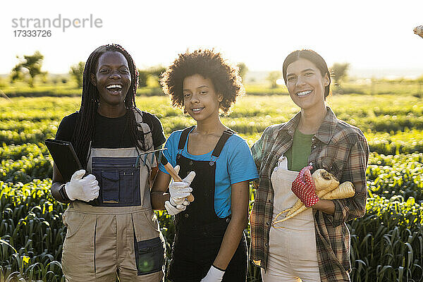 Fröhliche Landarbeiter mit Mädchen  die zusammen auf einem Bauernhof stehen