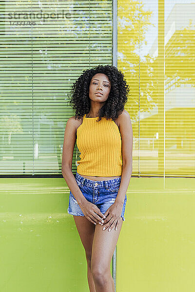Junge Frau steht vor einem grün-gelben Fenster